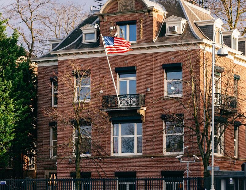 Discover a grand historic building adorned with the US flag in Amsterdam.