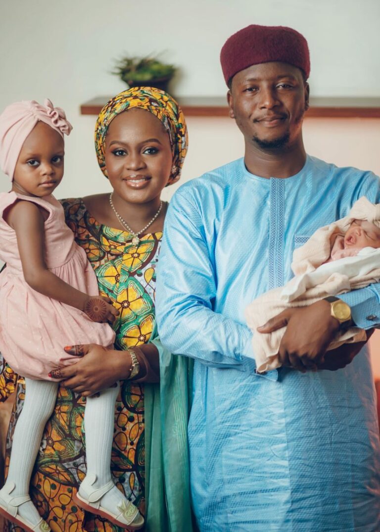 Happy Nigerian family in traditional attire posing indoors.