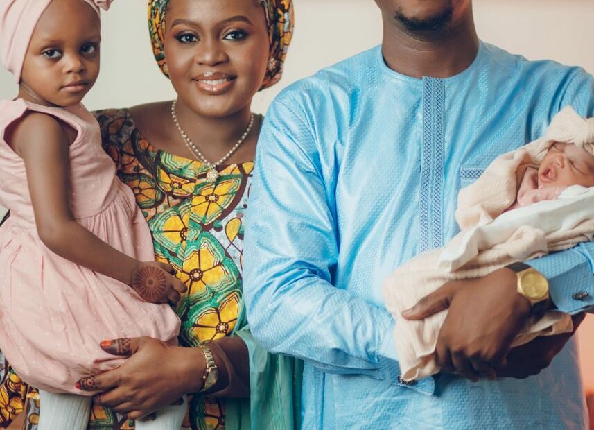 Happy Nigerian family in traditional attire posing indoors.