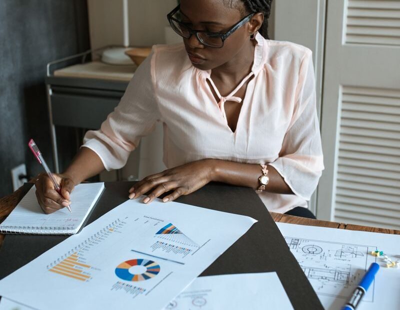 African businesswoman concentrating on planning with charts and diagrams in a modern workspace.