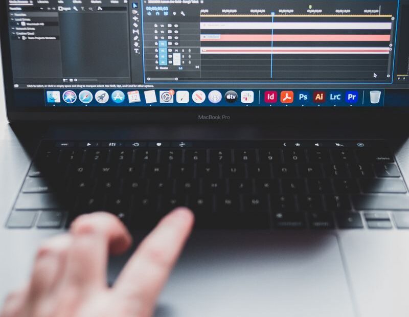 Crop unrecognizable male programmer typing on netbook while working on project and creating music